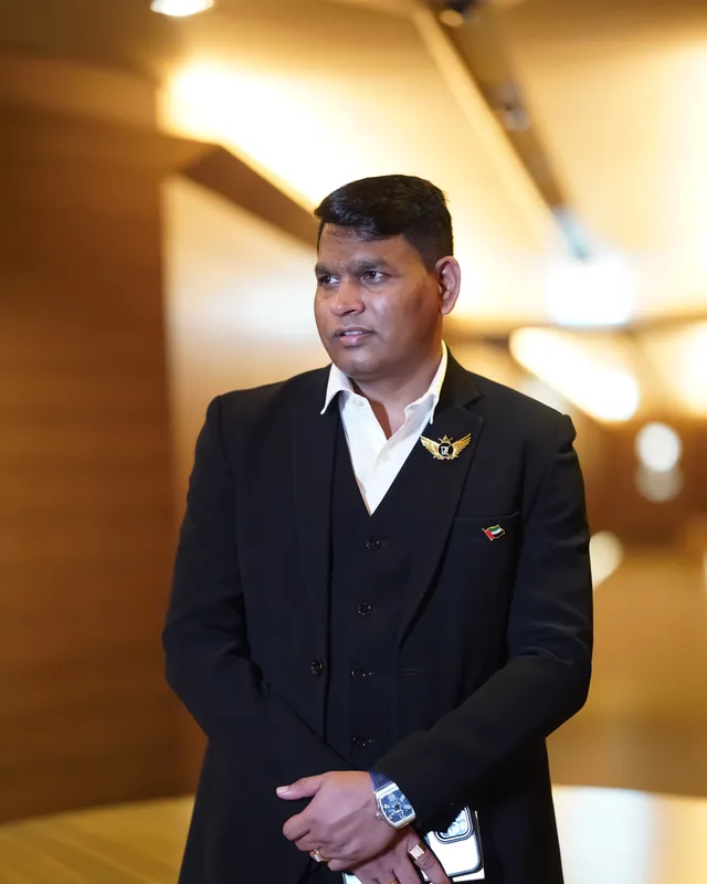 Dr. Rajendra Upadhye in a black suit, standing in a warmly lit room