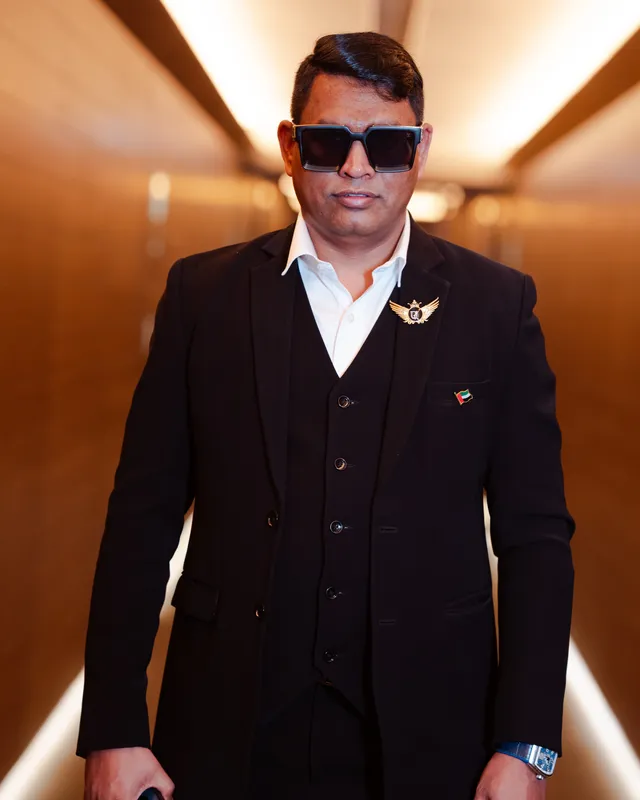 Dr. Rajendra Upadhye in a black three-piece suit and sunglasses