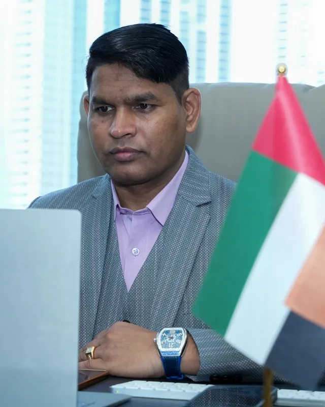 Dr. Rajendra Upadhye at his desk with the UAE and India flags