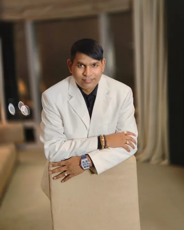 Dr. Rajendra Upadhye in a white blazer, leaning on a chair